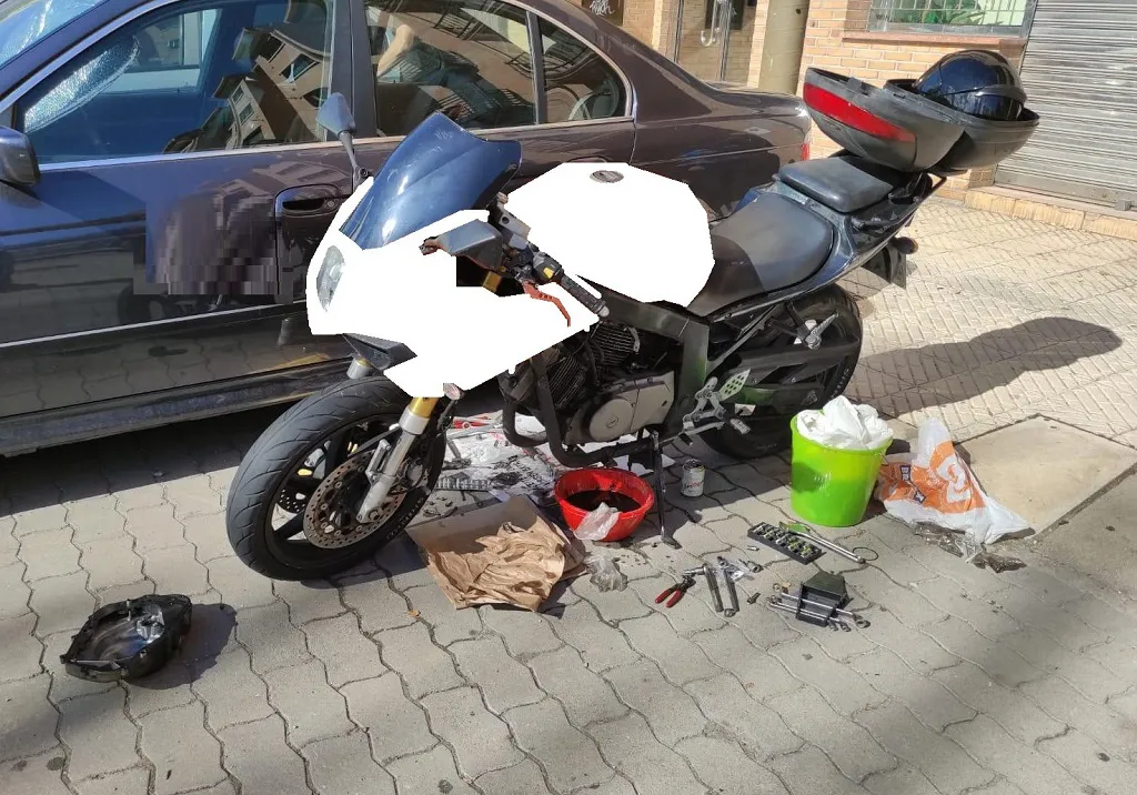 Se cree que la calle es un taller y cambia el aceite de su moto en medio de la acera